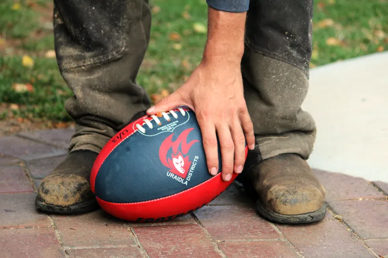 A work boot resting on a navy and red Uraidla Districts football