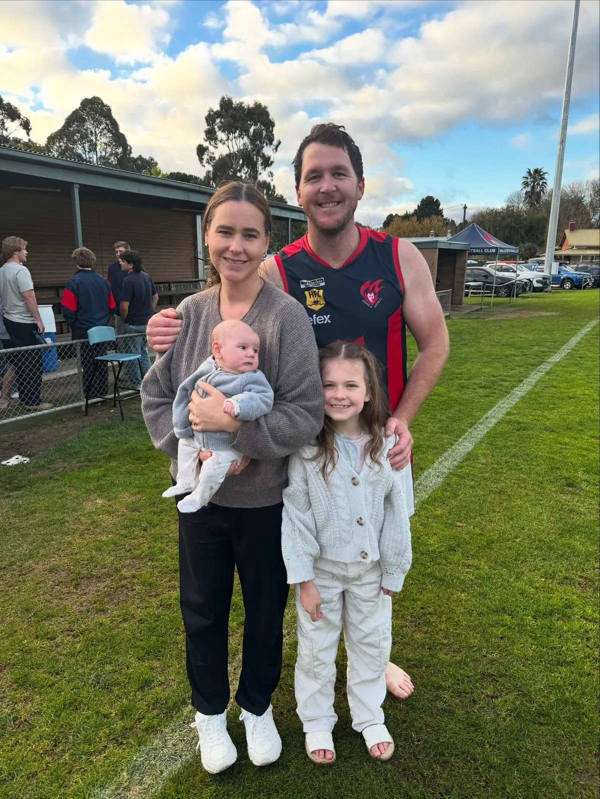 A Uraidla player in his guernsey with his family on the oval boundary